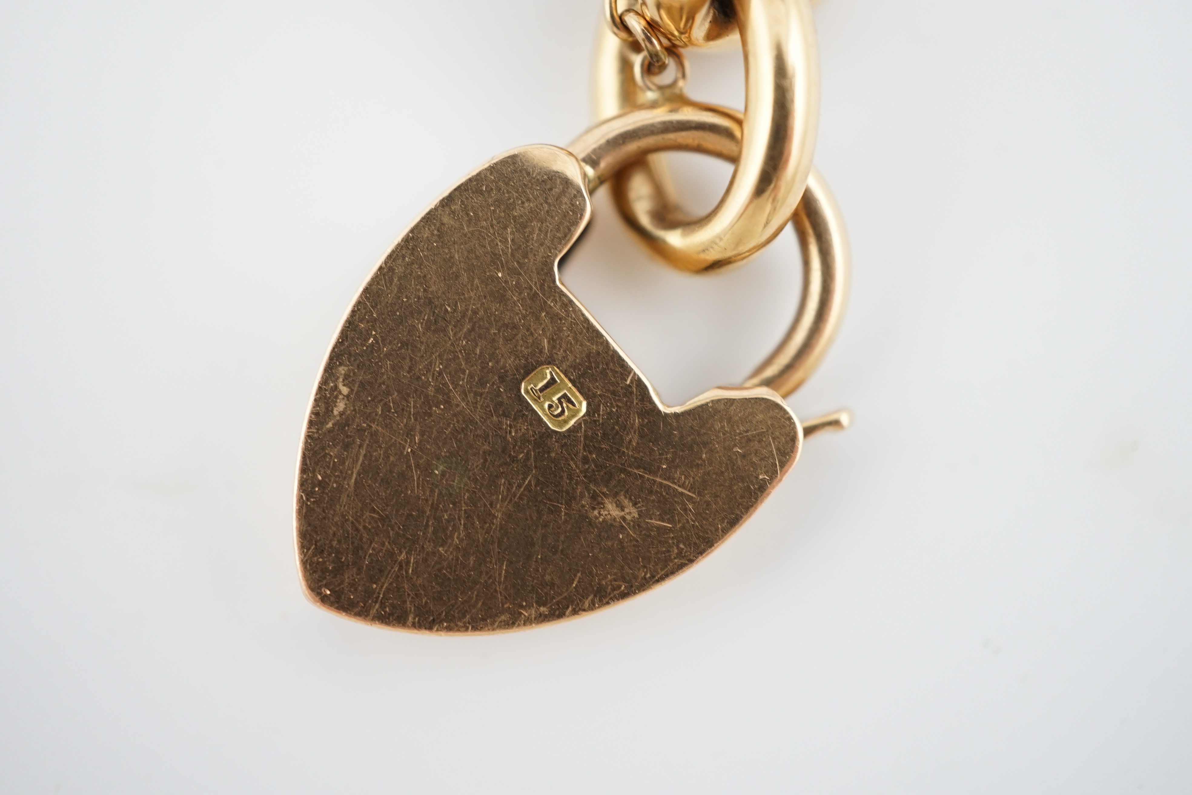 An Edwardian 15ct gold curb link bracelet, with heart shaped padlock clasp